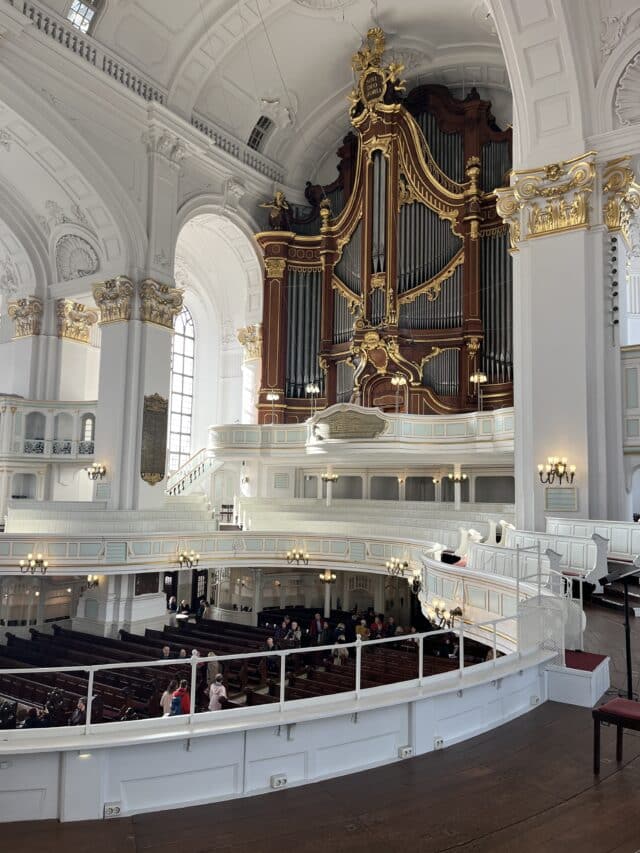 Organ hall with white walls and gold accents around the silver pipes